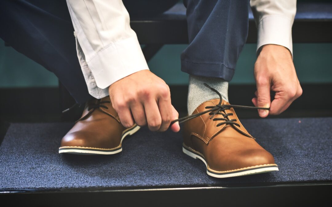 person tying brown leather shoes